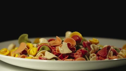 Colorful Pasta Shapes Falling onto White Plate