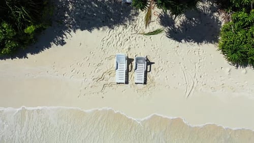 Beautiful flying tourism shot of a paradise sunny white sand beach and blue water background in colo