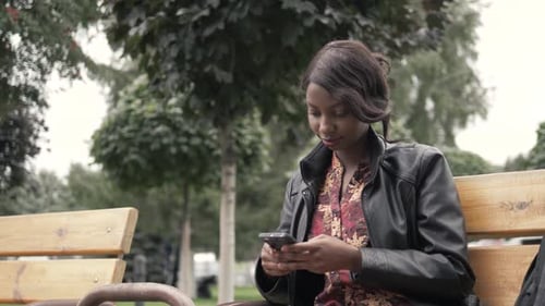 Woman Uses Smartphone on Park Bench