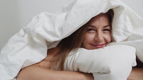 Mulher se escondendo debaixo do edredom