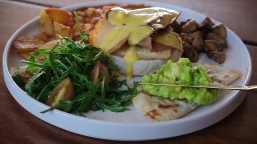 Gold Knife Spreads Guacamole on Breakfast Dish