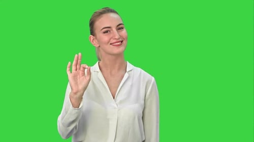 Glückliche junge Frau zeigt OK-Zeichen auf grünem Bildschirm, Chroma-Key