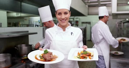 Smiling Chef Showing Two Dishes to Camera