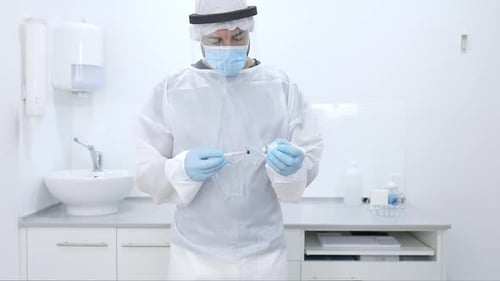 Crop doctor filling syringe with drug in hospital