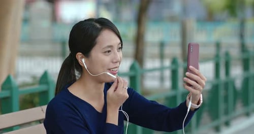 Woman talk on the video call on mobile phone in the park