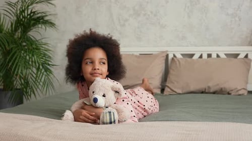 Girl Hugging Teddy Bear on Bed Indoors
