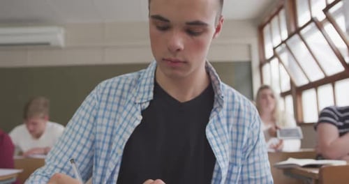Caucasian boy writing in high school class