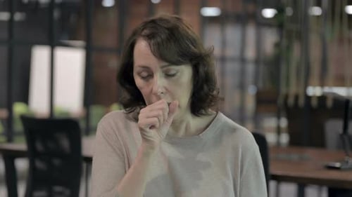 Mature Woman Coughing in Office Environment
