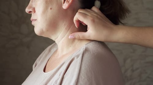 Hand Examines Woman's Neck in Close Up