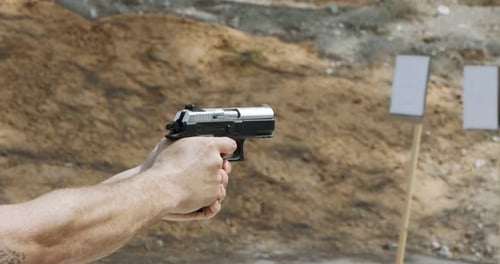Movimiento lento de una pistola de mano disparando en un campo de tiro con el cartucho volando