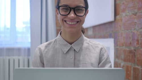 Woman Smiling Working at Laptop in Office