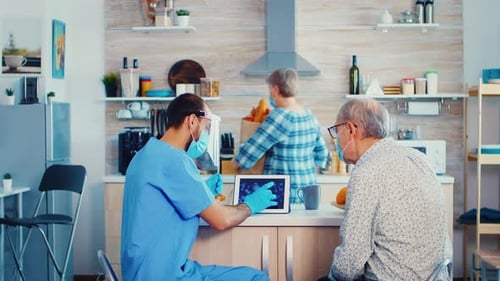 Doctor Explains Virus to Senior Man in Kitchen