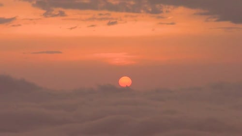 Sun Rises over Orange Sky and Clouds