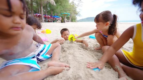 4K Group of Diversity children playing sand with beach toy together at the beach on summer vacation.