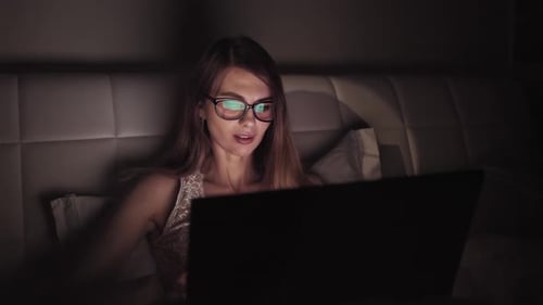 Woman Using Laptop Computer at Night in Bed