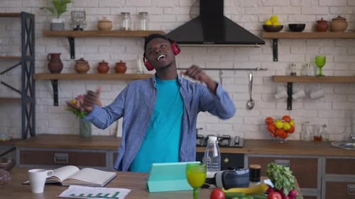 Young Adult Dancing in Kitchen with Headphones On