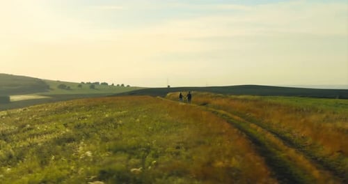 Two Tourists Walk on Hilly Terrain a Panoramic Shot From the Copter