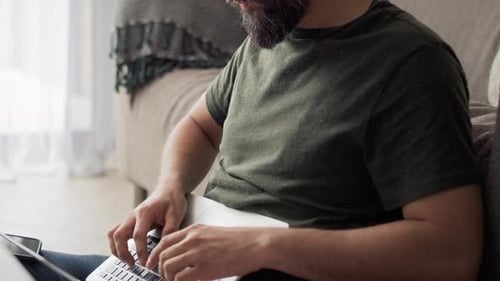Man Works on Laptop While Sitting on Floor