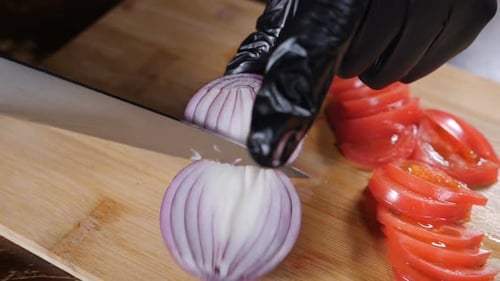 Knife Cuts Red Onion on Cutting Board