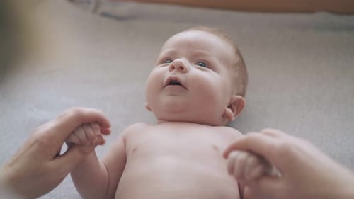 Caregiver Holds Hands of Newborn Baby on Changing Table