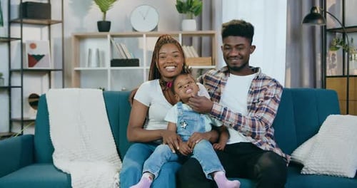 Happy Family Smiling on Couch Together in Home