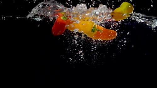 Colorful Peppers Splashing Into Water in Slow Motion