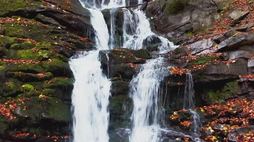 Narrow Stream Falling Down Mountain Slope in Autumn Forest