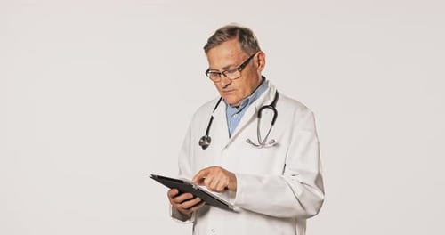 Mature Doctor Using Tablet in Studio Setting