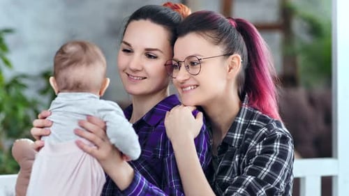 Loving Women Hold Baby and Embrace Indoors