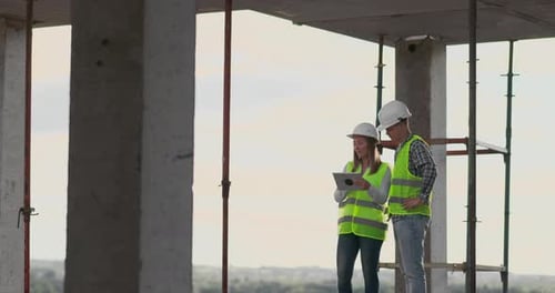 Two Construction Engineers Discuss Plans on Tablet