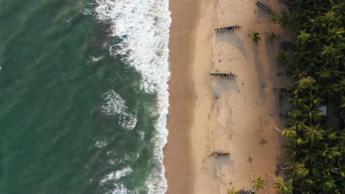 Ocean waves break on a tropical beach with canoes and palm trees. Zanzibar, Africa. 4K