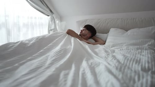 Wide Shot Sleeping Man Waking Up in Bedroom at Home in the Morning
