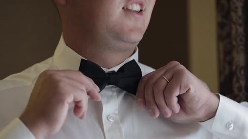 Close Up of Man Adjusting Black Bow Tie