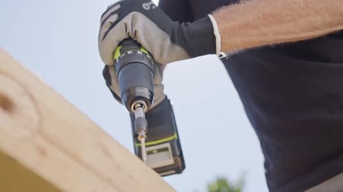Slow motion of a man using an electric screwdriver to drive a screw into wood