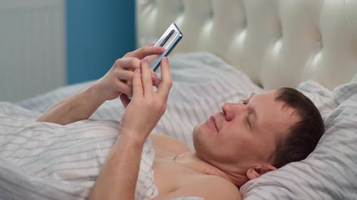 Young Adult Using Smartphone While Lying in Bed