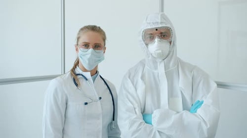 Portrait of Man and Woman Doctors in Protective Uniform Standing in Clinic