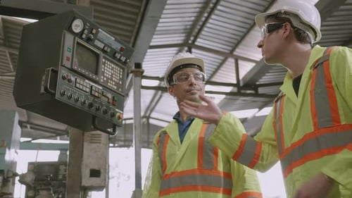 Two maintenance man and partner work with system of machine in industrial factory.