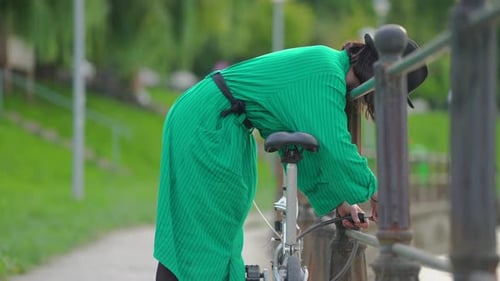 Woman Pumps Bike Tire in Green Urban Park