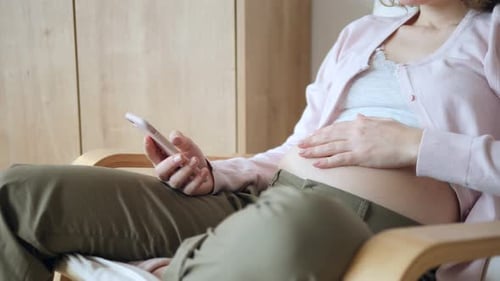 Pregnant Woman Relaxing with Mobile Phone at Home
