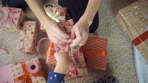 Family Wrapping Christmas Presents Together on the Floor