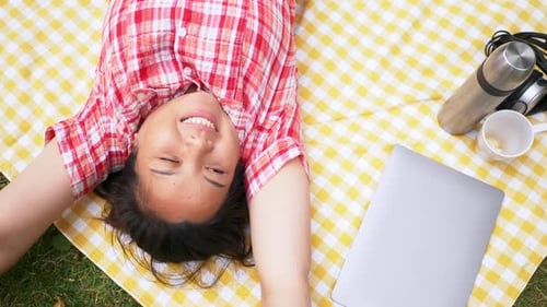 Top view of Aisan woman lying on mat and looking up to the sky at the park