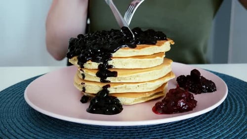 Pancakes Stacked High with Blueberry Sauce Being Cut