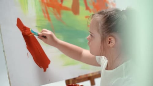 Child Painting on Canvas with Orange Paint