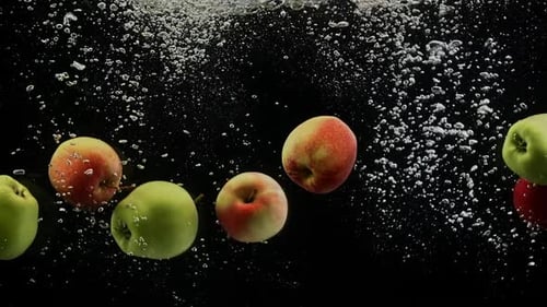 Ripe Fruits Colorful Apples Falling Into Water with Splash and Bubbles Black Background
