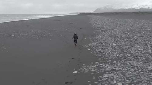 Rising Follow Shot of Woman Running Along a Beach.
