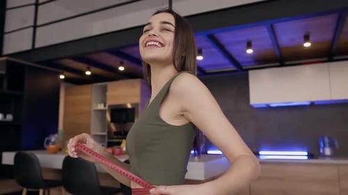 Brunette est heureuse de voir son tour de taille montrant à la caméra ses résultats à l'aide de ruban adhésif
