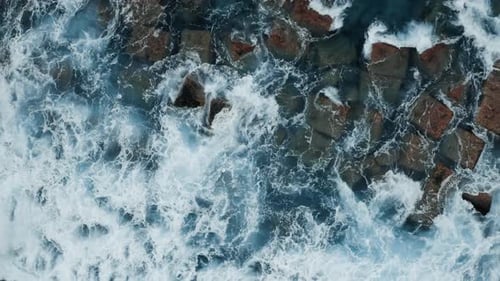 Aerial View of Waves Crashing on Rocky Shore