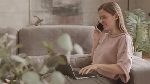 Woman working on laptop while talking on phone