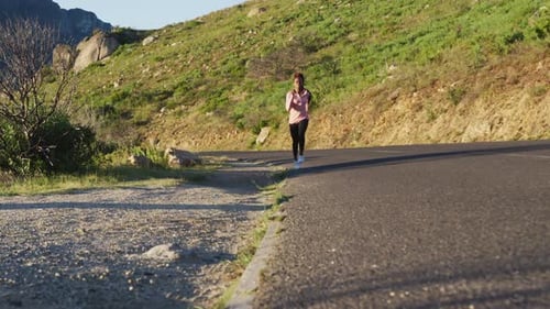 Woman Runs on Paved Road in Rural Setting