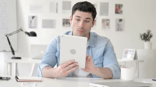 Man Reacts to Tablet Content in Bright Office